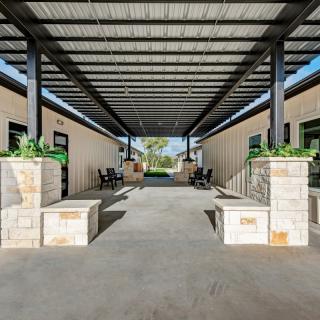 A modern outdoor covered corridor with benches and planters.