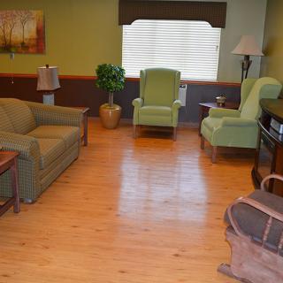 A cozy living room with a sofa, two armchairs, and wooden flooring.
