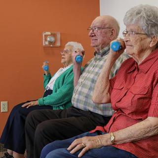 Seniors exercising with small weights in a fitness class.