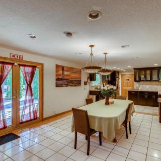 A spacious dining room with a table set for four, leading into an adjacent kitchen area.