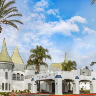 A whimsical castle-like building with turreted roofs and palm trees under a bright blue sky.