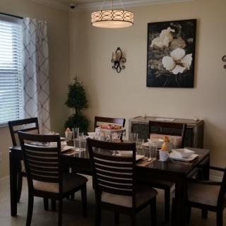 A neatly arranged dining room with a table set for a meal under a decorative chandelier.
