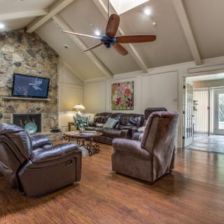 A cozy living room with leather sofas, a stone fireplace, and hardwood floors.
