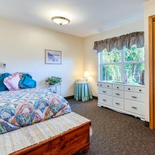 A cozy bedroom with a bed, dresser, and a window providing natural light.