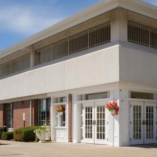 A modern two-story commercial building with large glass doors and floral decorations.