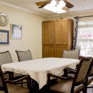 A cozy dining room with a table and chairs, decorated with wall art and a ceiling fan.