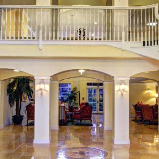 A spacious and elegant lobby featuring columns, a staircase, and comfortable seating.