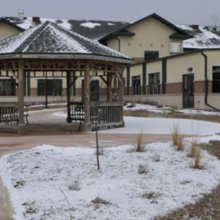 A snowy courtyard featuring a gazebo and nearby building in winter.