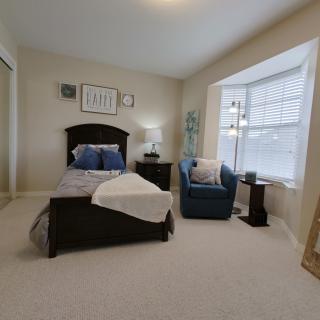 A cozy bedroom with a single bed and an armchair by the window.