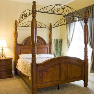 A beautifully designed bedroom featuring a wooden four-poster bed with intricate carvings and elegant drapery.
