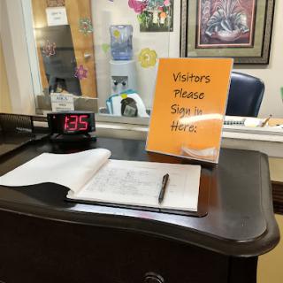 A visitor check-in desk with a sign requesting guests to sign in.