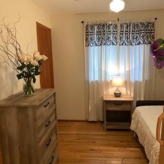 A cozy bedroom with wooden furniture, a bed, and decorative floral arrangements.
