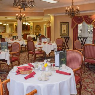 An elegant dining room with neatly set tables and chandeliers.