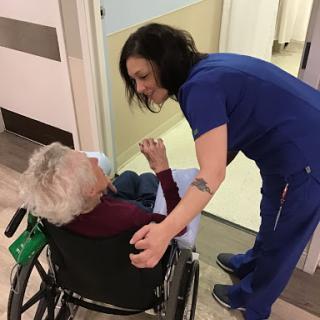A compassionate nurse interacts with an elderly patient in a wheelchair, showcasing the importance of care in healthcare settings.