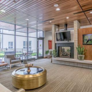A modern lobby with comfortable seating, a fireplace, and large windows.