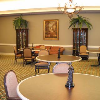A cozy lobby area featuring round tables, comfortable seating, and decorative plants.