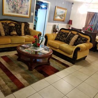 A cozy living room with comfortable sofas, a wooden coffee table, and decorative cushions. The space is adorned with artwork and a colorful rug.