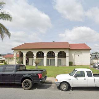 A residential house with a red roof and arched windows, flanked by two parked trucks.