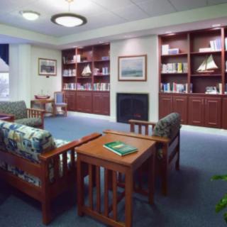 A cozy library space with comfortable seating and bookshelves surrounding a fireplace.