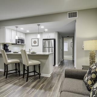 Modern open-concept living room and kitchen with neutral colors and stylish bar stools.