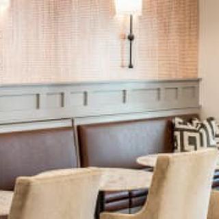 Cozy cafe seating area with tables, chairs, and wall lighting.
