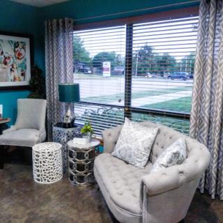 A stylish living room featuring a comfortable sitting area with modern decor, offering a pleasant view outside.