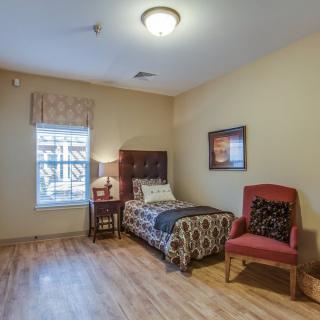 A cozy bedroom with a single bed, wooden flooring, and comfortable seating.