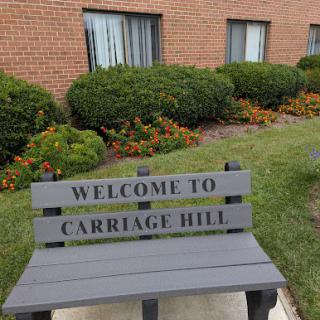 A welcoming bench at Carriage Hill, surrounded by lush landscaping.