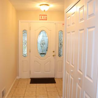 A well-lit hallway with an ornate entrance door and tile flooring.