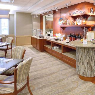 A modern dining area with a buffet setup, featuring tables and chairs for guests.