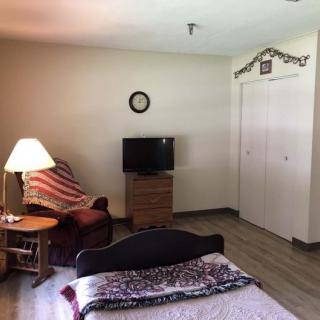 A cozy bedroom with a bed, television, and a comfortable chair.