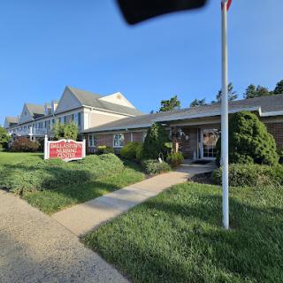 A well-kept building with a flag in front and clear signage, surrounded by lush greenery.