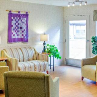 A cozy living room with a sofa, chairs, and wall art.