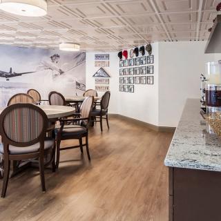A cozy cafe interior with elegant round tables, chairs, and aviation-themed wall decor.