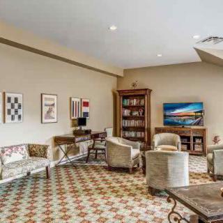 A cozy living room with comfortable seating, a bookshelf, and decorative artwork on the walls.