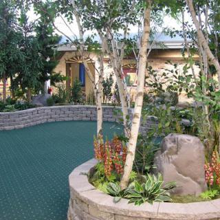 A serene outdoor garden featuring lush greenery, trees, and decorative stones.
