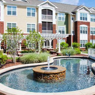 A modern apartment complex with a landscaped courtyard featuring a fountain.