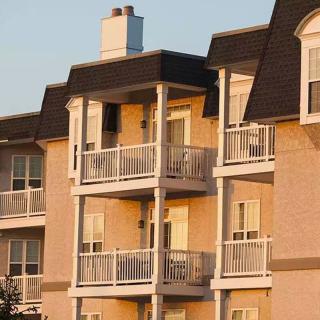 A view of an apartment building with multiple balconies at sunset.