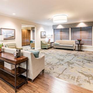 A spacious and cozy living room with modern decor, featuring comfortable sofas, a large patterned carpet, and elegant artwork on the walls.