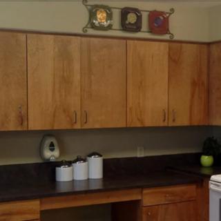 A kitchen with wooden cabinets, a dark countertop, and decorative elements.
