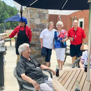 A group of seniors enjoying a social gathering under the patio umbrella.