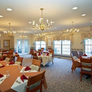 A spacious and elegantly decorated dining room with multiple tables set for guests.