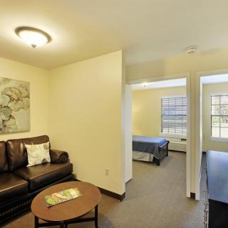 A cozy apartment interior featuring a living room with a sofa and coffee table, adjacent to a bedroom.