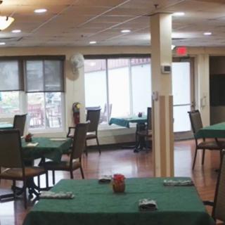 An empty dining area with green tablecloths and neatly arranged chairs.