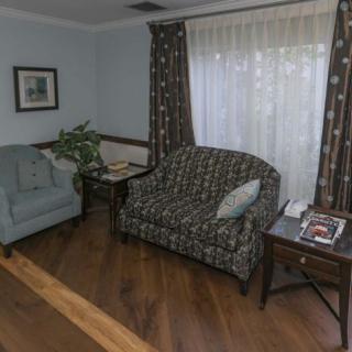A cozy living room with a sofa, armchair, and wooden flooring.