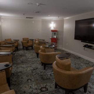 A comfortable lounge area with armchairs, a large television, and a popcorn machine.