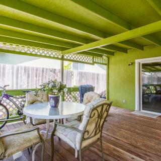 A cozy patio with a green-painted ceiling, featuring a table and chairs on a wooden deck, next to a bicycle.