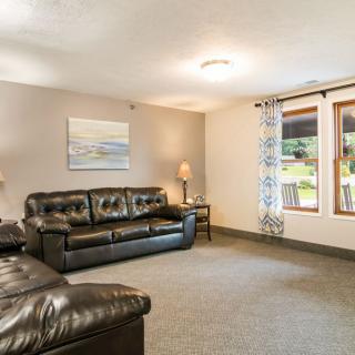 A cozy living room with leather sofas and large windows.