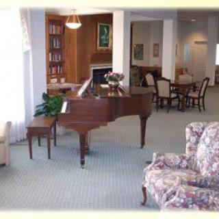 A cozy living space featuring a grand piano, bookshelves, and comfortable seating.