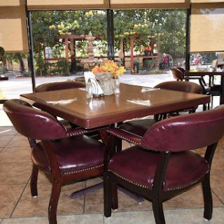 A cozy restaurant dining area with a wooden table and burgundy chairs, offering a view of the outdoors.